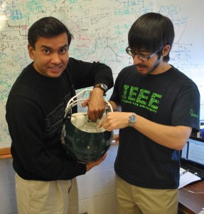 One of the many applications of self-powered sensors is creating a “smart” helmet that can detect and diagnose concussions automatically. Here, Chakrabartty (left) is testing out a prototype. Image courtesy of Shantanu Chakrabartty.