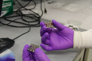 Tenghooi Goh holds organic solar cells with P3HT (the red cell) that absorbs blue-green light, and PTB7 (the blue cell) that absorbs yellow-red light. The researchers combined these polymers in a single solar cell to harness the energy of a wider range of light wavelengths. Photo by Genevieve Sertic.