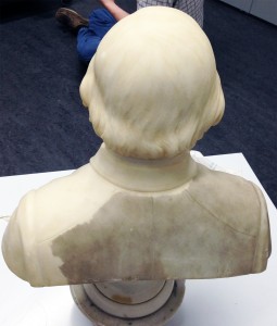The dark, dirty surface is visible through the middle back, on over the left shoulder. Lasers have exposed the clean marble surface on the right shoulder. 